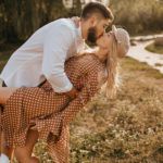 guy in white shirt inclining his girlfriend during gentle and passionate kiss couple embracing amid park