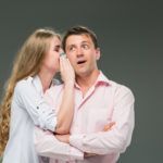 portrait of young couple standing against gray wall