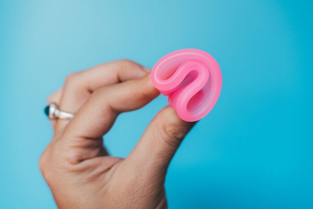 woman holding a pink menstrual cup on blue royalty free image 1603889862