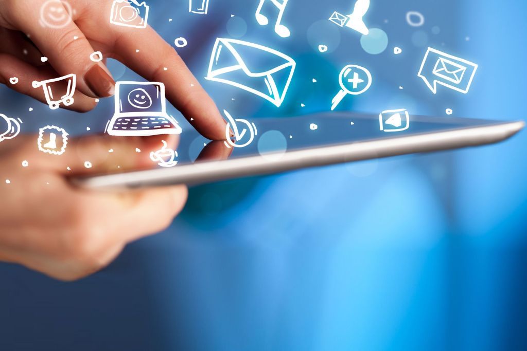 Mano tocando una tablet de la que salen iconos de email y redes sociales
